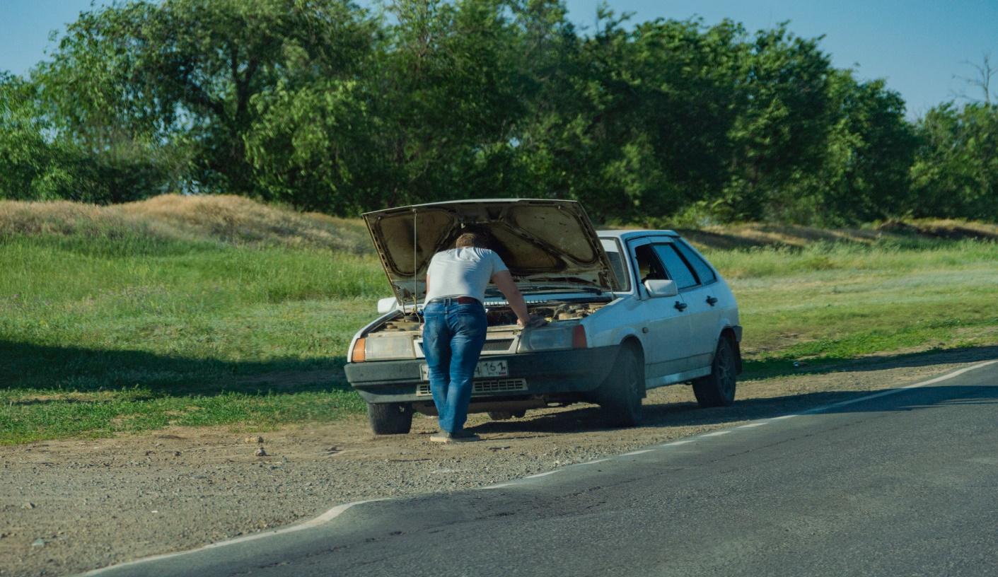 A person opens the hood of a car to check the battery.