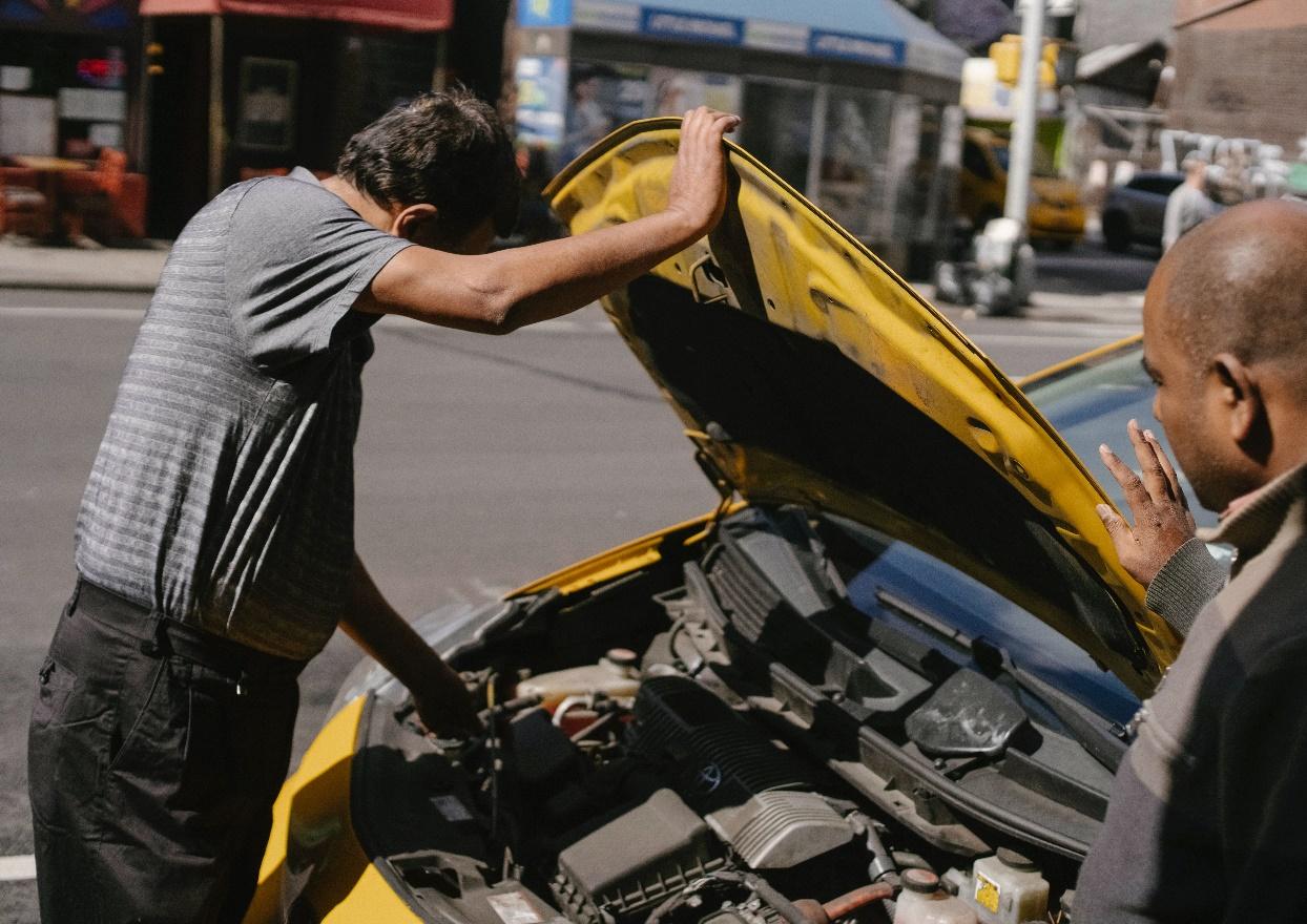 A person removes the positive terminal of a car battery.